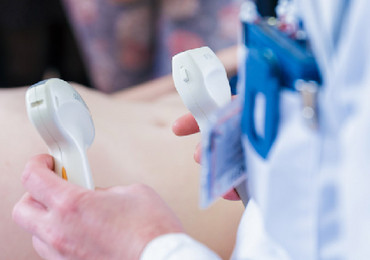 Ein Arzt hält ein Ultraschallgerät in der Hand.